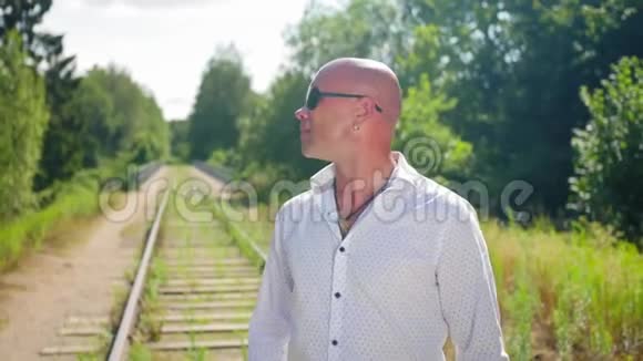 一个秃头的人走在一座废弃的铁路桥上桥上长满了草中弹视频的预览图
