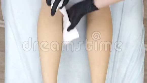 美容师在加糖后擦拭消毒女孩脚美容师戴着橡胶手套视频的预览图