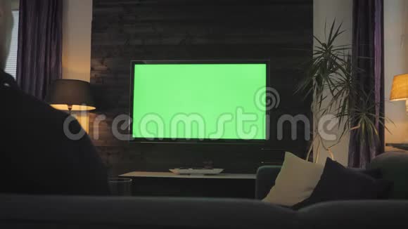 绿屏男在客厅看电视在肩膀上射击视频的预览图