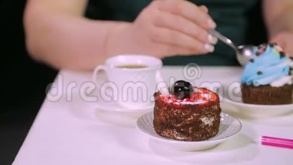 女人在咖啡馆里的黑色背景上拿一杯咖啡和一个带有甜点的勺子视频的预览图