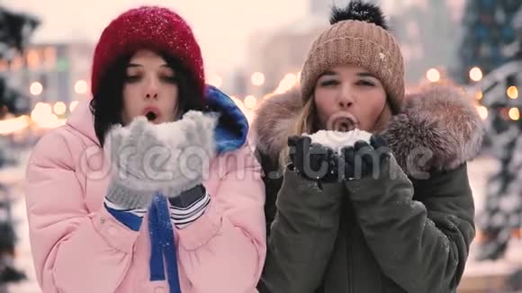 快乐的女性朋友在冬天吹雪慢动作视频的预览图