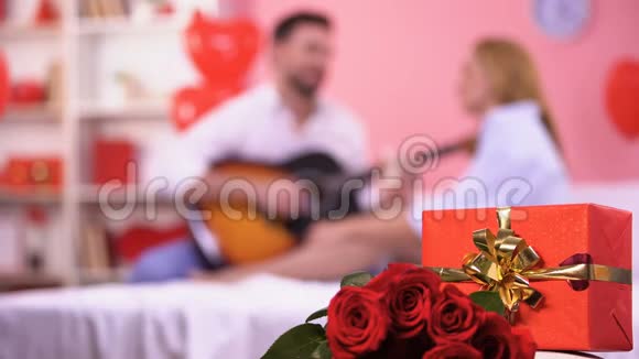 红色礼盒和一束玫瑰特写男弹吉他浪漫旋律视频的预览图