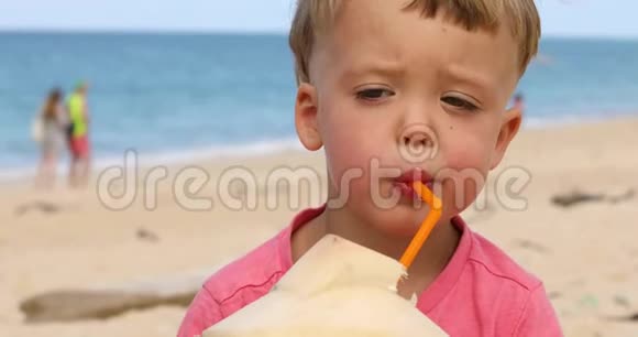 可爱的儿童在海滩上喝椰子水视频的预览图