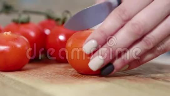 一个女人在大自然中做饭女手特写一个大红鲜番茄用菜刀切下视频的预览图