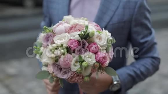 他手里拿着结婚花束在街上的新郎粉色衬衫蓝色夹克视频的预览图