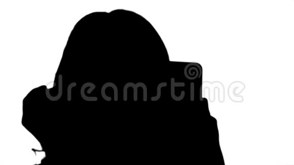 剪影女人在睫毛上涂上黑色睫毛膏看着她的手机视频的预览图