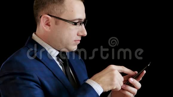一个穿黑色背景西装的中年男人的轮廓一个商人通过他的智能手机在互联网上工作视频的预览图