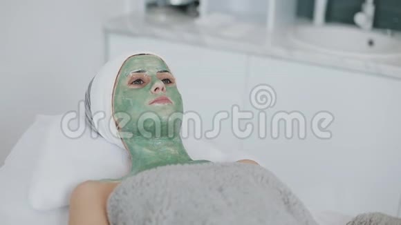 水疗沙龙里的女人面具美丽的女孩躺在沙发上戴着绿色面具在美容诊所慢慢视频的预览图
