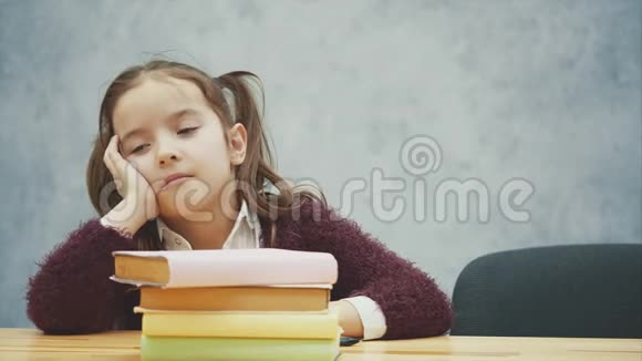 一个小女学生拿着很多书睡在桌子上许多家庭作业或考试对年轻人来说压力很大视频的预览图