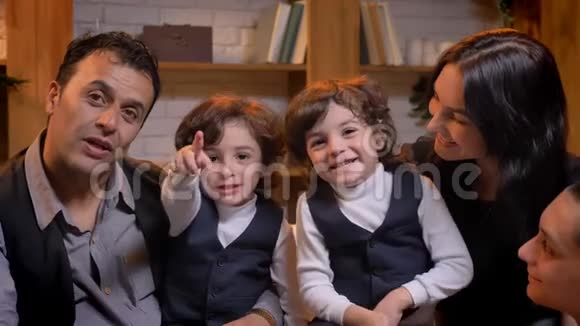 阿拉伯家庭坐在沙发上微笑地指着客厅里摄像机上的手指视频的预览图
