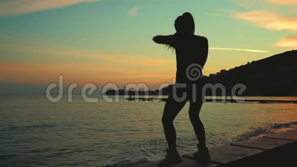 运动员在日落时在海边的海滩上将拳击表演空中视频的预览图