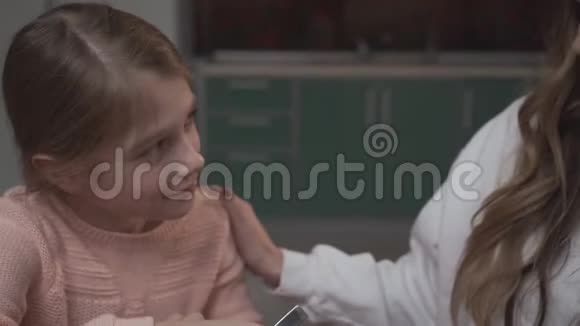 小女孩把鸡蛋和面粉混合在碗里坐在厨房的桌子上和她的姐姐在一起年长女孩赞美视频的预览图
