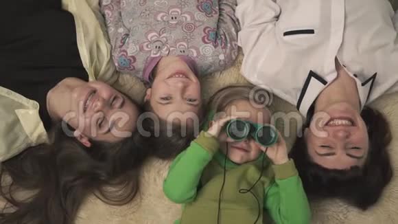 家庭肖像快乐的姐姐和年轻的男孩和女孩躺在地毯上的房间有趣的小男孩视频的预览图
