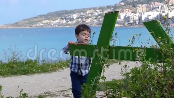可爱的两岁小男孩在公园大海的绿色破桌上攀爬背景视频的预览图