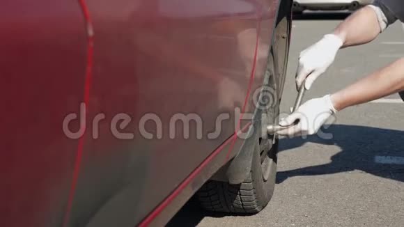 一个没有经验的戴白手套的人正试图在他那辆破破烂烂的红色汽车里旋转一个轮子视频的预览图