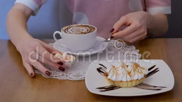 一位年轻的女士把棉花糖和美味的蛋糕放在咖啡上视频的预览图