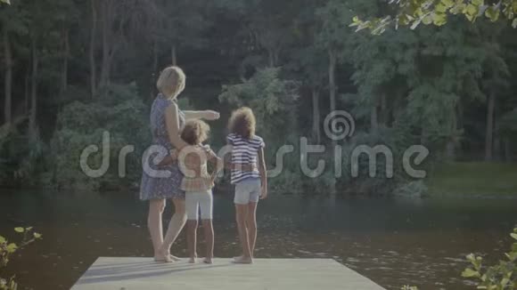 不同的家庭站在湖边的木码头上视频的预览图