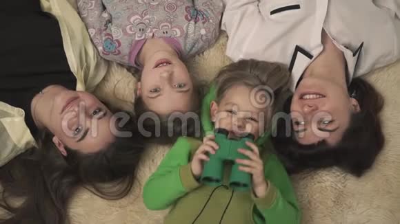 幸福的姐姐和年轻的男孩和女孩躺在房间的地毯上的家庭肖像有趣的小男孩视频的预览图
