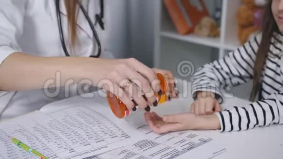 在儿科医生的办公室里女医生给一个小女孩一个维生素果冻从罐子特写视频的预览图