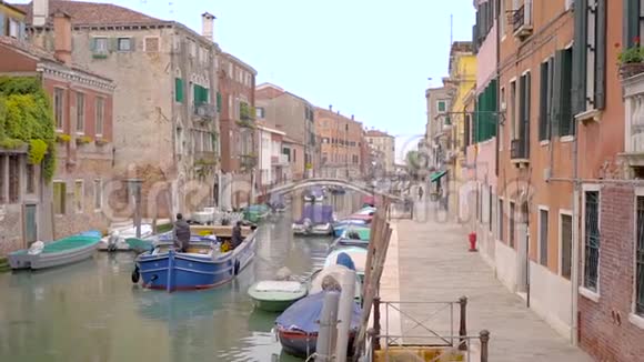 在意大利威尼斯有一条水道的街道在旧房子的框架里一座桥和一艘船视频的预览图