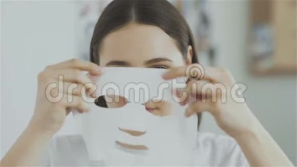 女人把化妆面具戴在脸上看着镜头视频的预览图