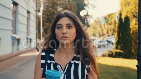 在市中心散步的时候年轻漂亮的女人正在喝咖啡视频的预览图