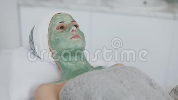 水疗沙龙里的女人面具美丽的女孩躺在沙发上戴着绿色面具在美容诊所慢慢视频的预览图