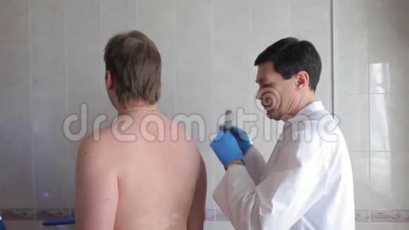 一位男性医生用电子医疗设备检查病人皮肤医疗技术4K视频的预览图