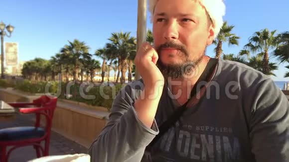 在棕榈海咖啡馆戴着圣诞帽留着胡子的烦恼男人的画像视频的预览图