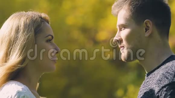 年轻夫妇接吻男人用秋叶掩面浪漫约会特写视频的预览图