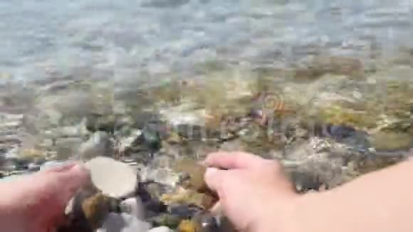 女孩手里拿着海卵石女性双手特写海浪石质旅游和旅游视频的预览图