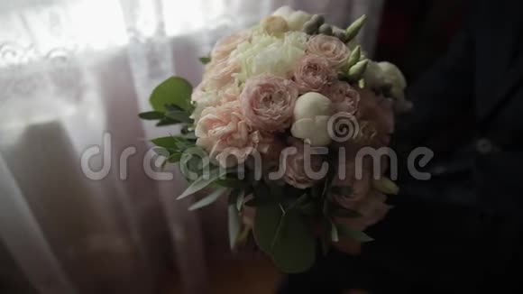 家里手里拿着结婚花束的新郎白色衬衫黑色领带夹克视频的预览图