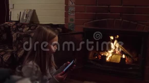 女孩在壁炉附近读电子书视频的预览图