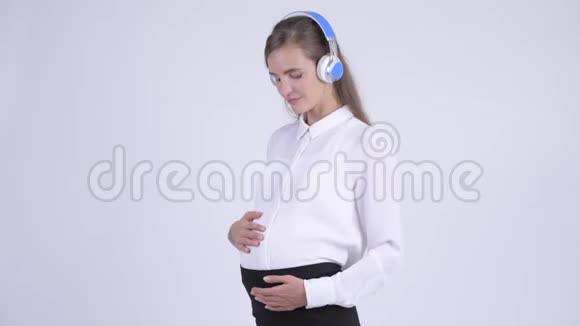 年轻快乐的怀孕女商人听音乐视频的预览图