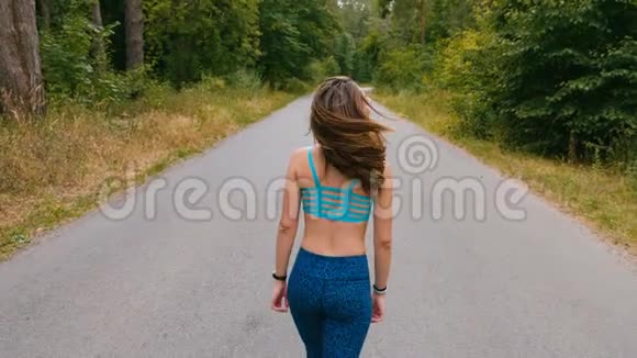 性感女孩在森林里的路上散步户外健身用定心丸射击视频的预览图