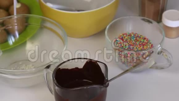 桌子上放着一块空白的饼附近是做流行蛋糕的原料巧克力和五颜六色的调料视频的预览图