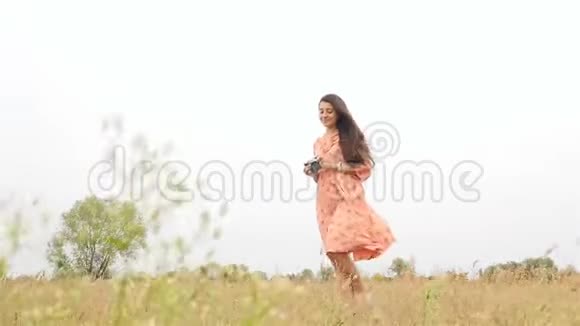 美丽的女孩拍摄大自然的照片田野上长满了绿草慢动作风吹发视频的预览图