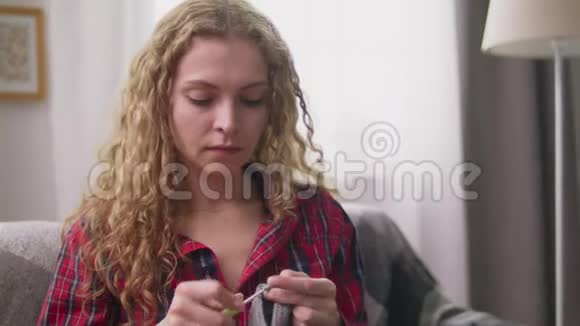 在舒适的家中手持倾斜镜头的女人编织钩针服装视频的预览图