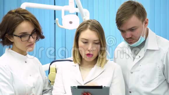 三位牙医在一个医疗柜里看着一片药片讨论诊断医学概念医务专业人员视频的预览图