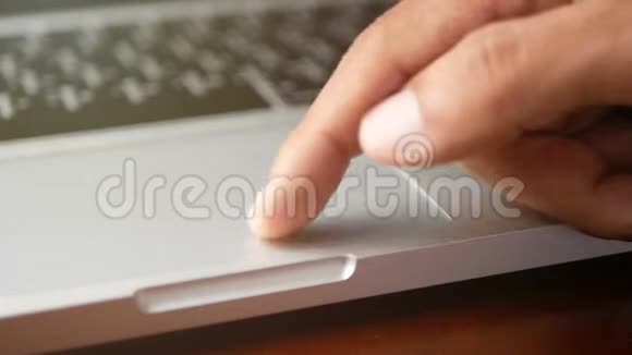 4K特写一个男人用手提笔记本电脑用手指用键盘触摸板或触控板滑动和放大视频的预览图