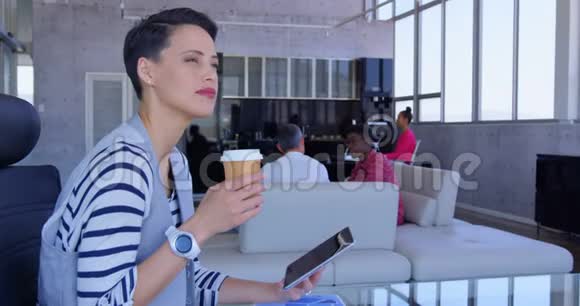 美丽的高加索女商人在现代办公室喝咖啡时使用数字平板电脑视频的预览图