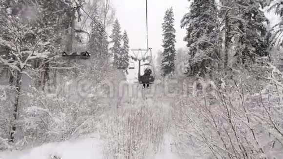 鸟瞰两座缆车飞越冬雪森林用小型滑雪板从滑雪坡上爬升视频的预览图
