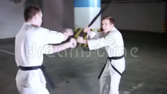 两个穿和服的年轻人在地下停车场训练他们的技能剑战视频的预览图