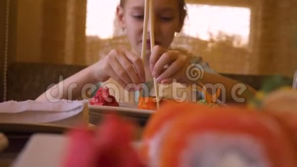 小女孩的嘴吃寿司和红色鲑鱼用木筷子视频的预览图