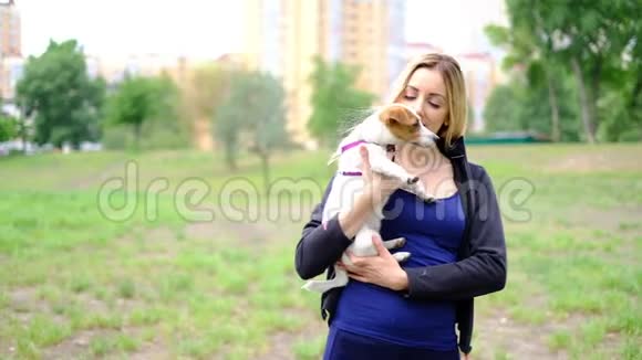 公园里金发的年轻苗条女子带着她的杰克罗素猎犬慢动作视频的预览图