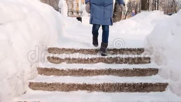 特写女人她的腿在雪梯楼梯上往下走白天下雪时在城市的冬季公园视频的预览图