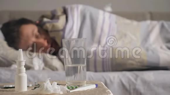年轻的病人躺在家里的床上吃一包药片视频的预览图