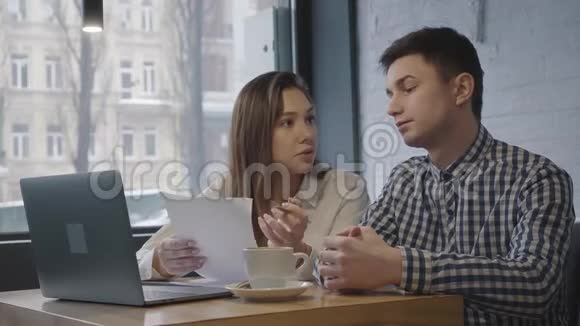 一个年轻人和女孩坐在一张桌子上在一家舒适的咖啡馆或餐馆的窗户附近有一台笔记本电脑朋友视频的预览图