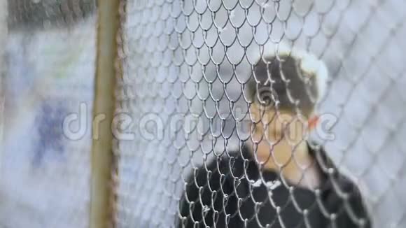 失去亲人的少年站在金属栅栏的庇护下用悲伤的眼神看着这个世界视频的预览图