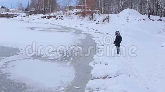 年轻人站在白雪覆盖的冰冻河岸上然后坐在雪地上视频的预览图